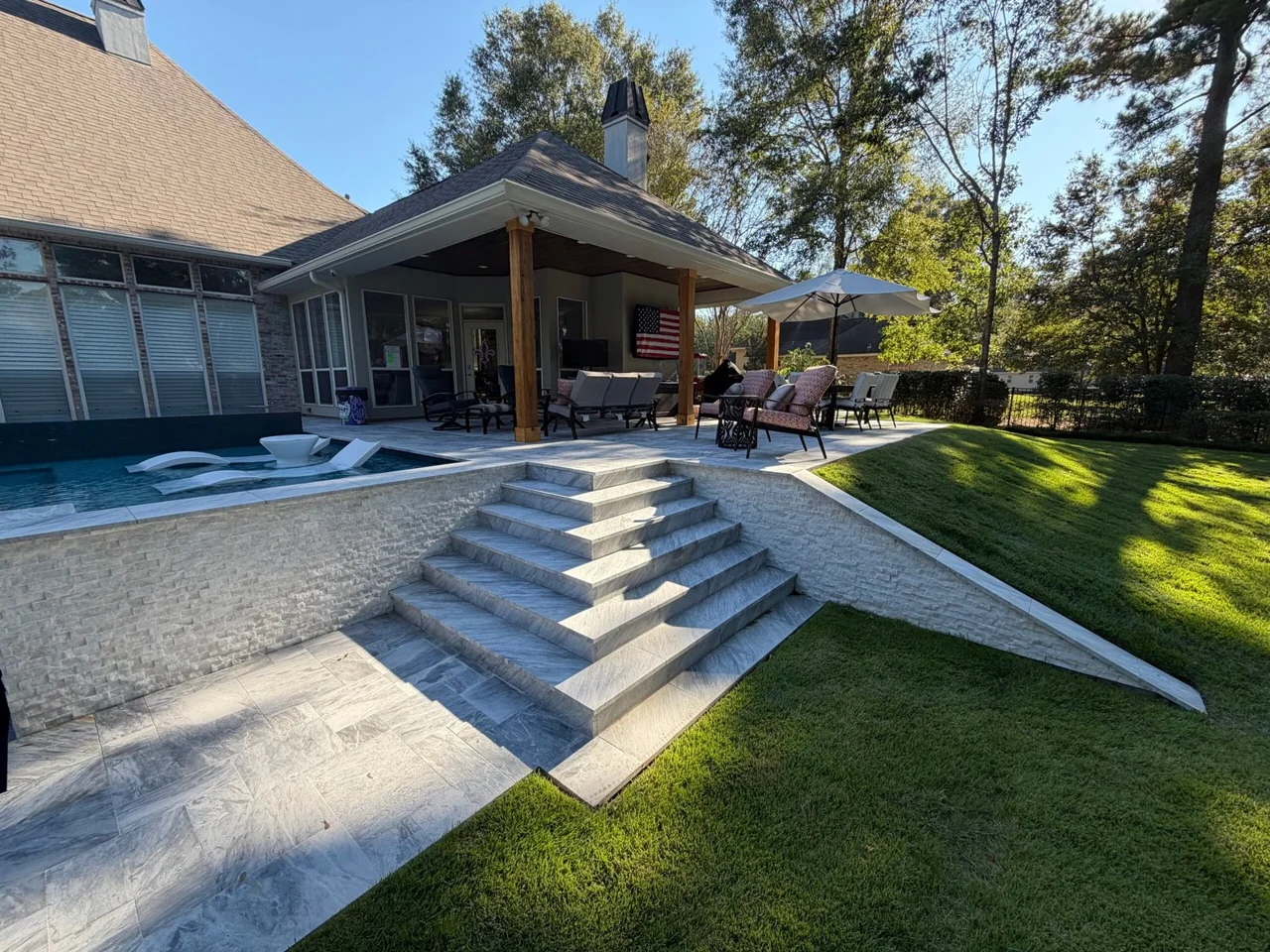 A real Cypress Pools custom pool with an integrated sun shelf and landscaped backyard